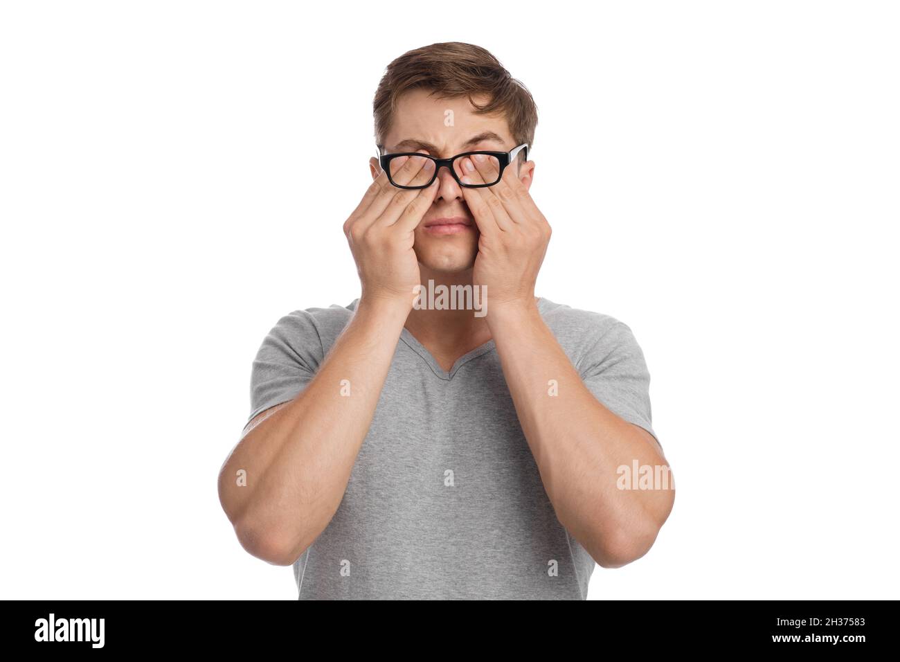 Tired young european man with eye pain, from glasses and rubs his eyes