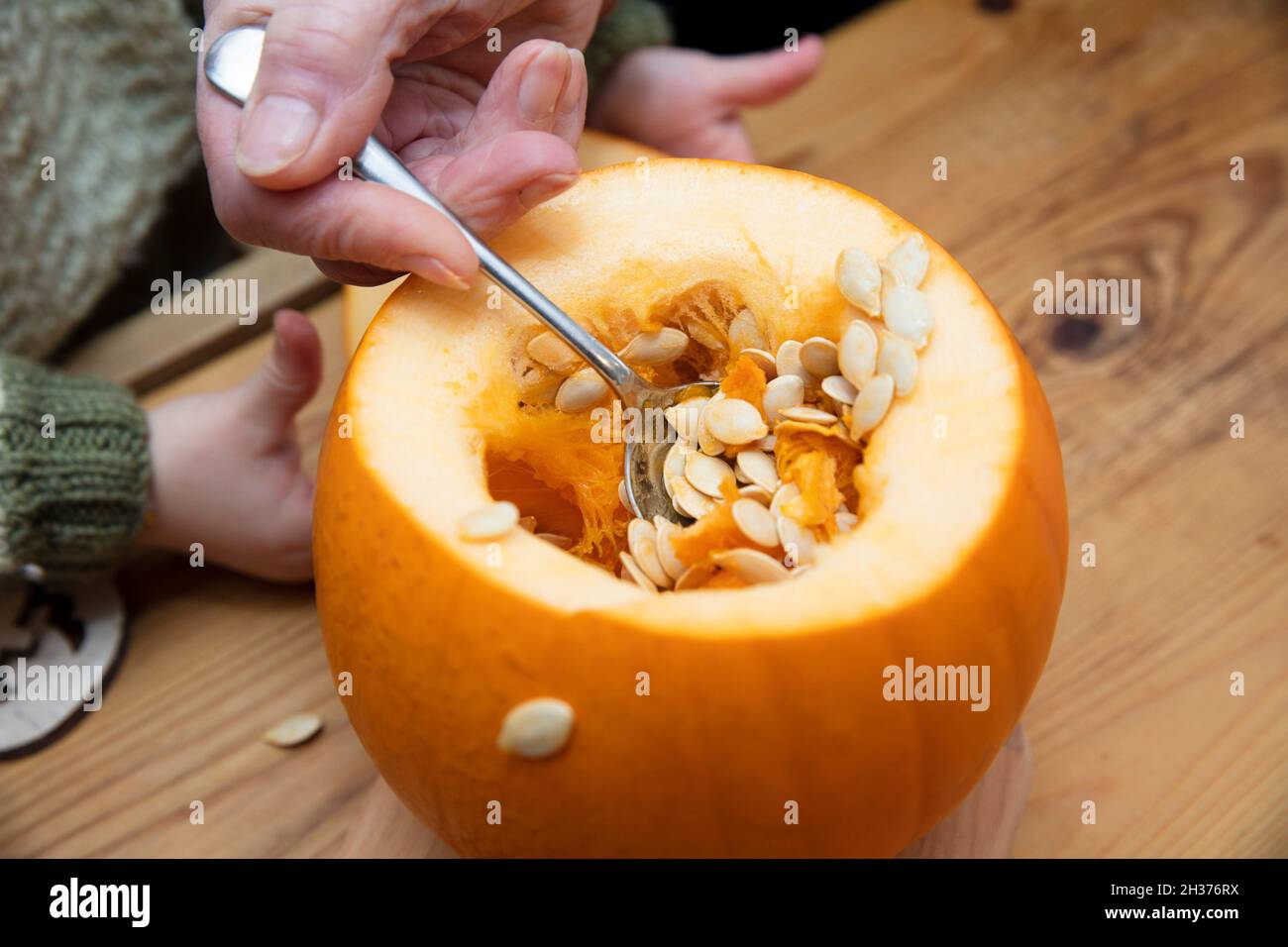 orange Halloween pumpkin being carved into a lantern decoration by a grandmother and child Stock Photo