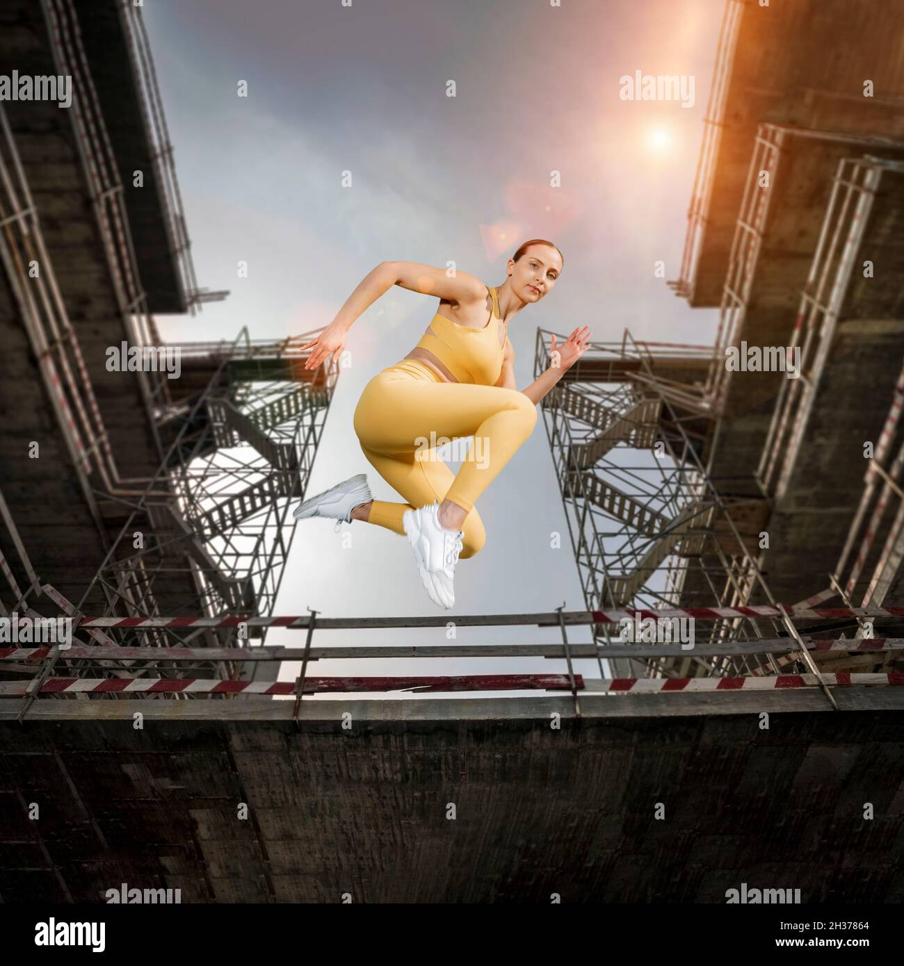 fit sporty woman running and jumping. Urban background. Free runner. Stock Photo