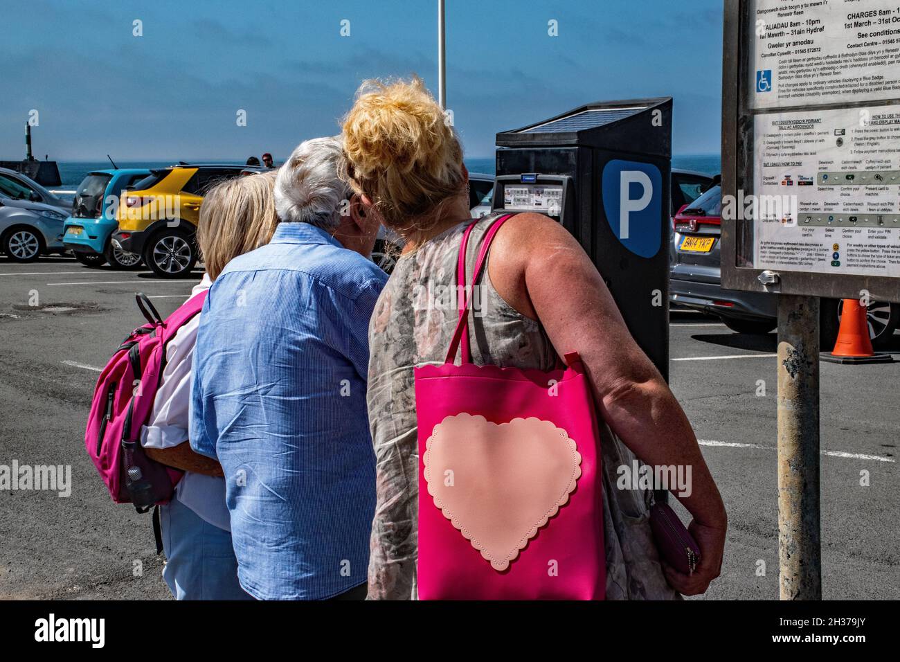 Holiday makers struggle with a Welsh parking meter. Stock Photo