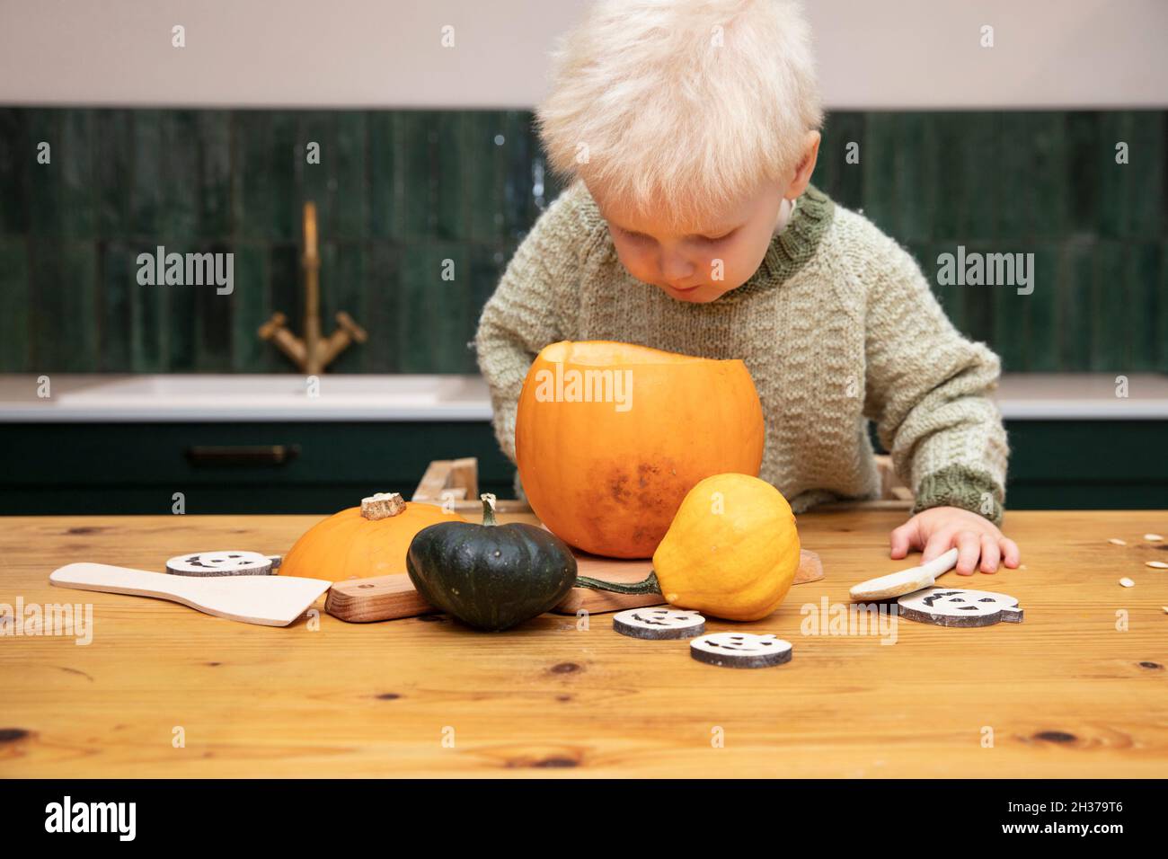 A cute young boy peering into a halloween pumpkin whilst making a lantern decoration Stock Photo