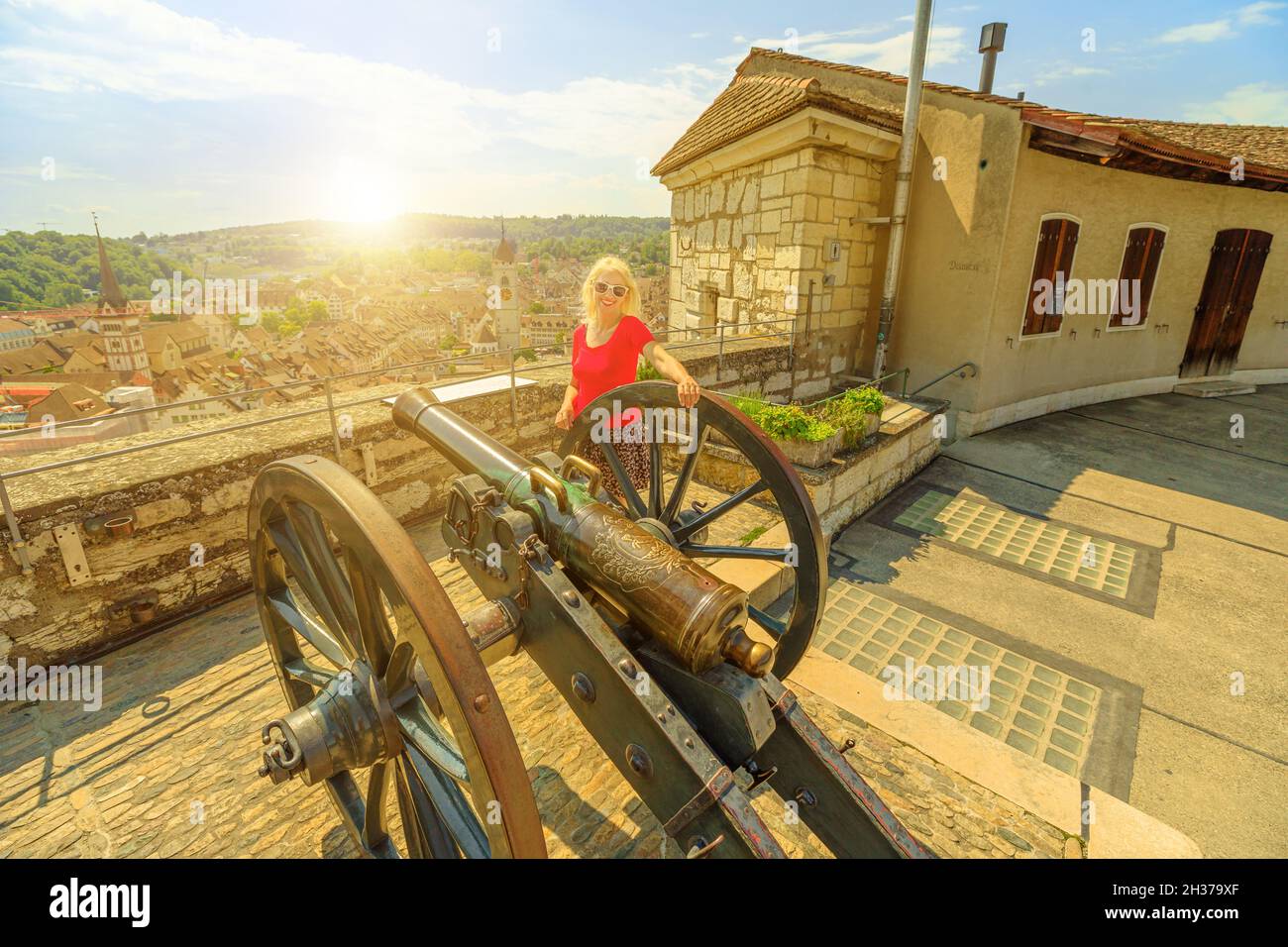 Blonde women by the cannon of Munot fortress at sunset on Schaffhausen. Swiss historic town with terraced vineyards on river Rhine. Swiss capital of Stock Photo