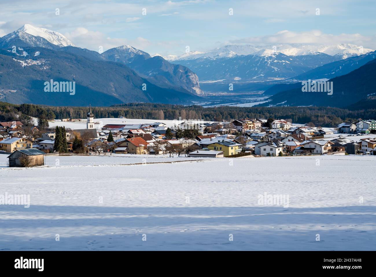 Sunny now covered alpine mountain village with view on Telfs, Wildermieming, Tirol, Austria Stock Photo