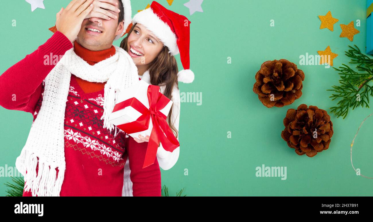 Composition of caucasian couple wearing santa hats holding present on ...