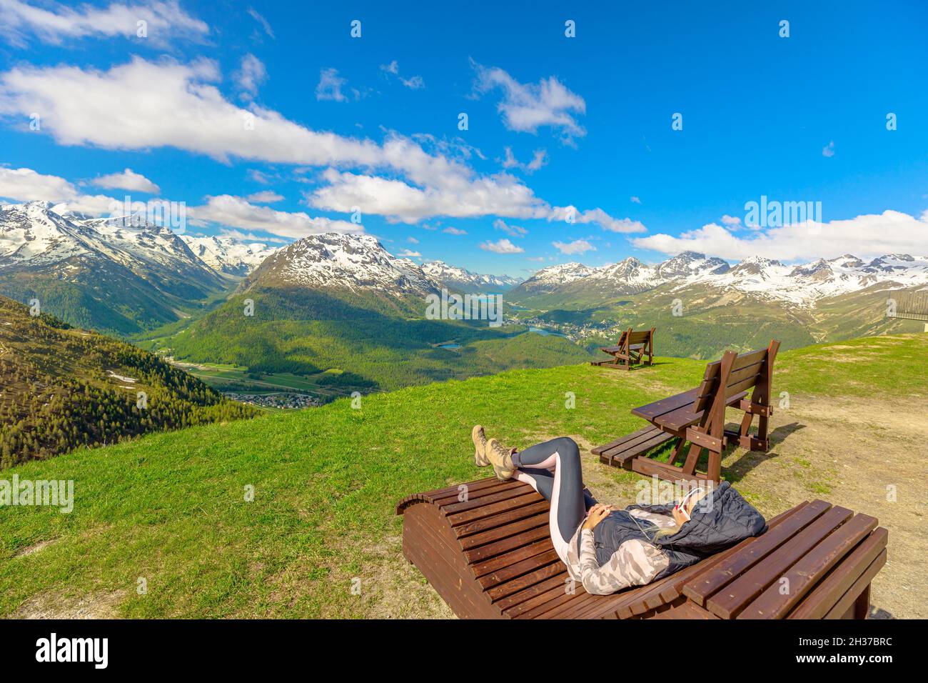 Woman resting on a bench on top of Muottas Muragl station of the famous funicular railway in Switzerland. Popular location for mountain excursions in Stock Photo