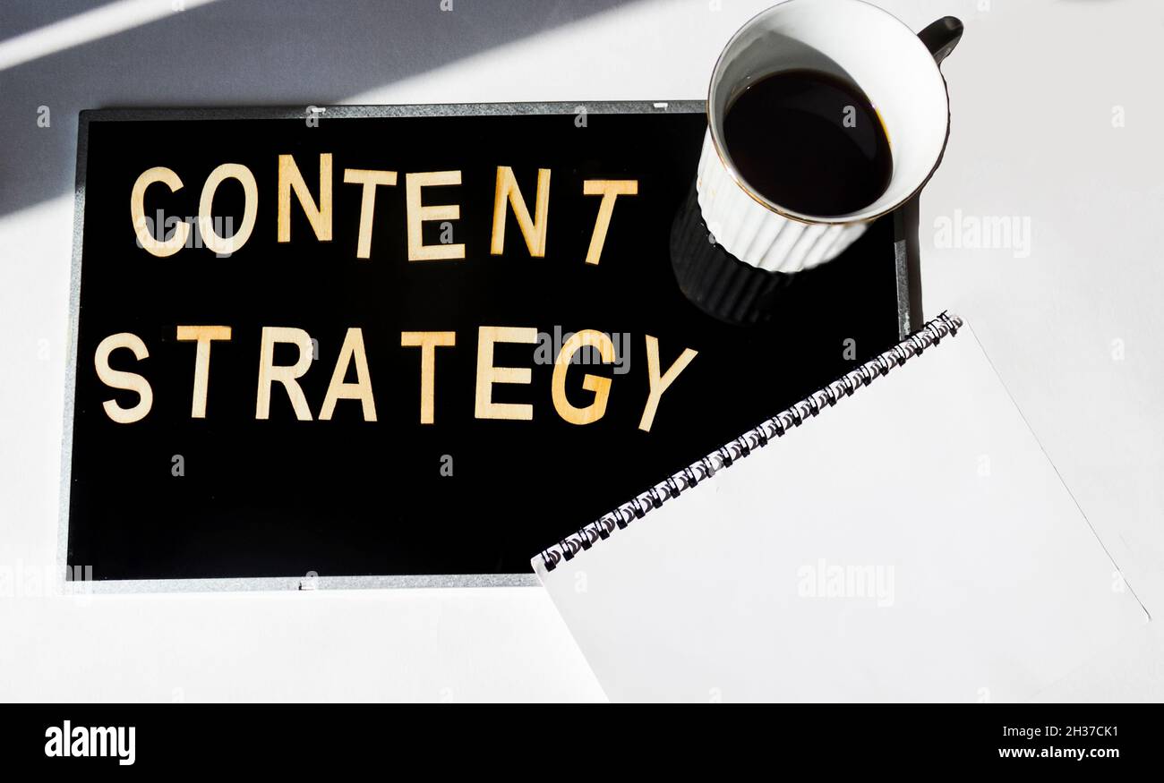 Content strategy word cloud on black background with notepad and coffee cup. Stock Photo