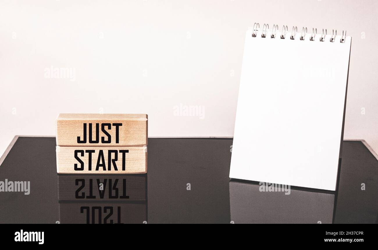 Just start action concept written on wooden blocks and black and white background. Next to an empty notepad for writing Stock Photo