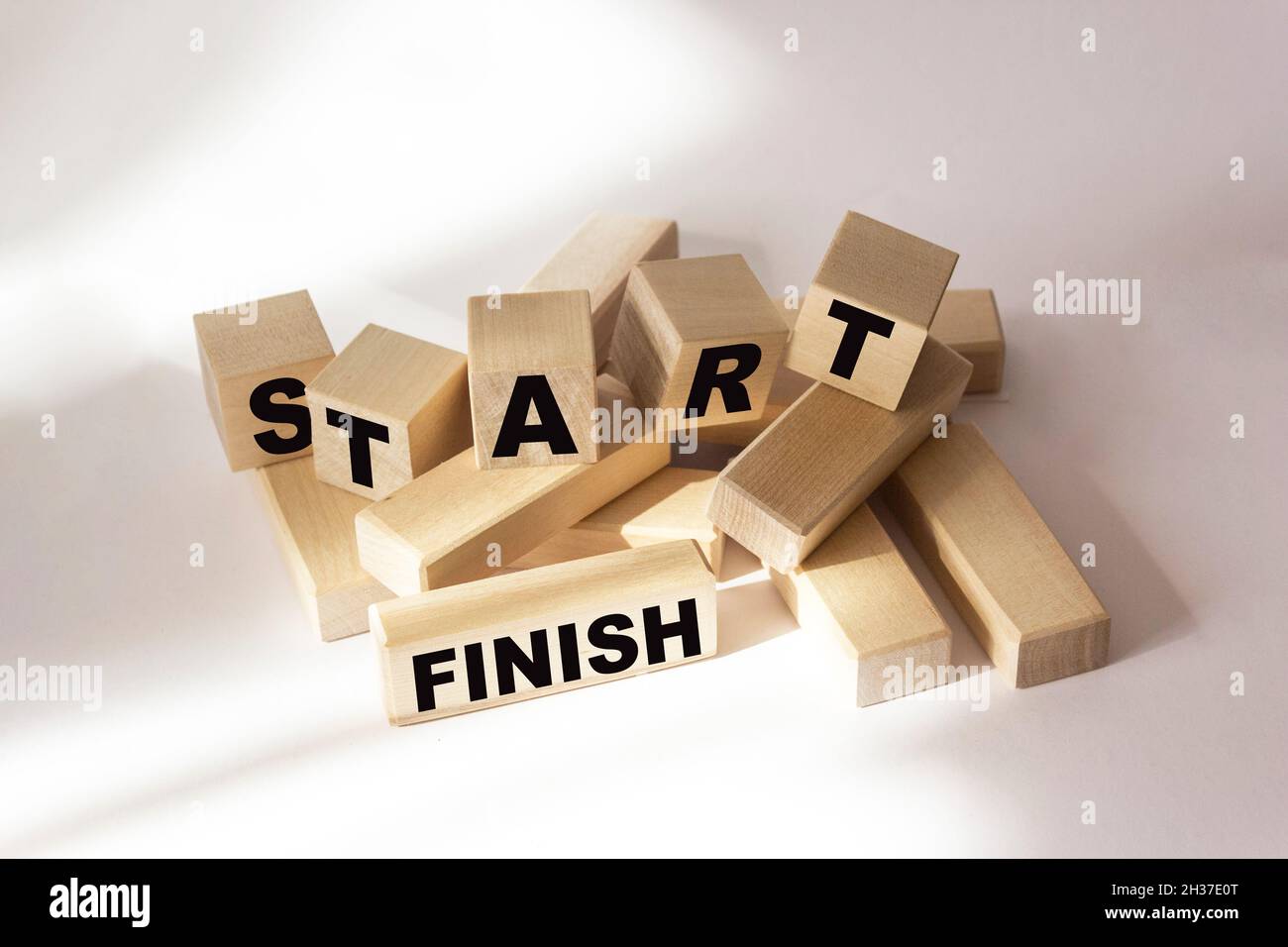 The words Start and Finish written on wooden blocks and a white background. Stock Photo