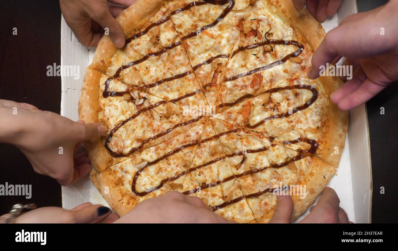Close-up Of People Hands Taking Slices Of Pizza. Close-up Of People Hands Taking Slices Of Pepperoni Pizza. Friends take pizza top view Stock Photo