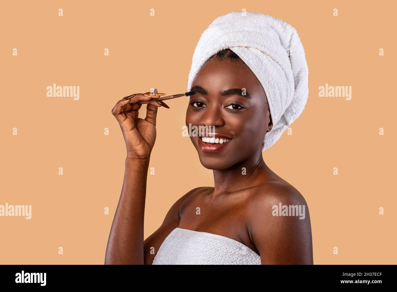 Portrait of smiling woman applying mascara on brows Stock Photo