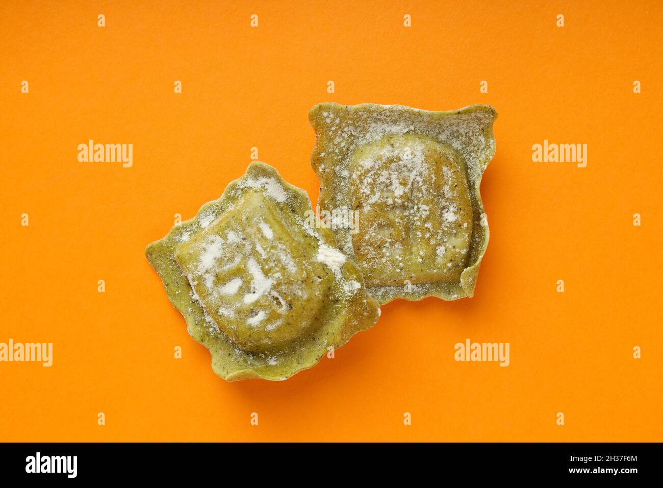 Raw ravioli with flour on orange background Stock Photo - Alamy