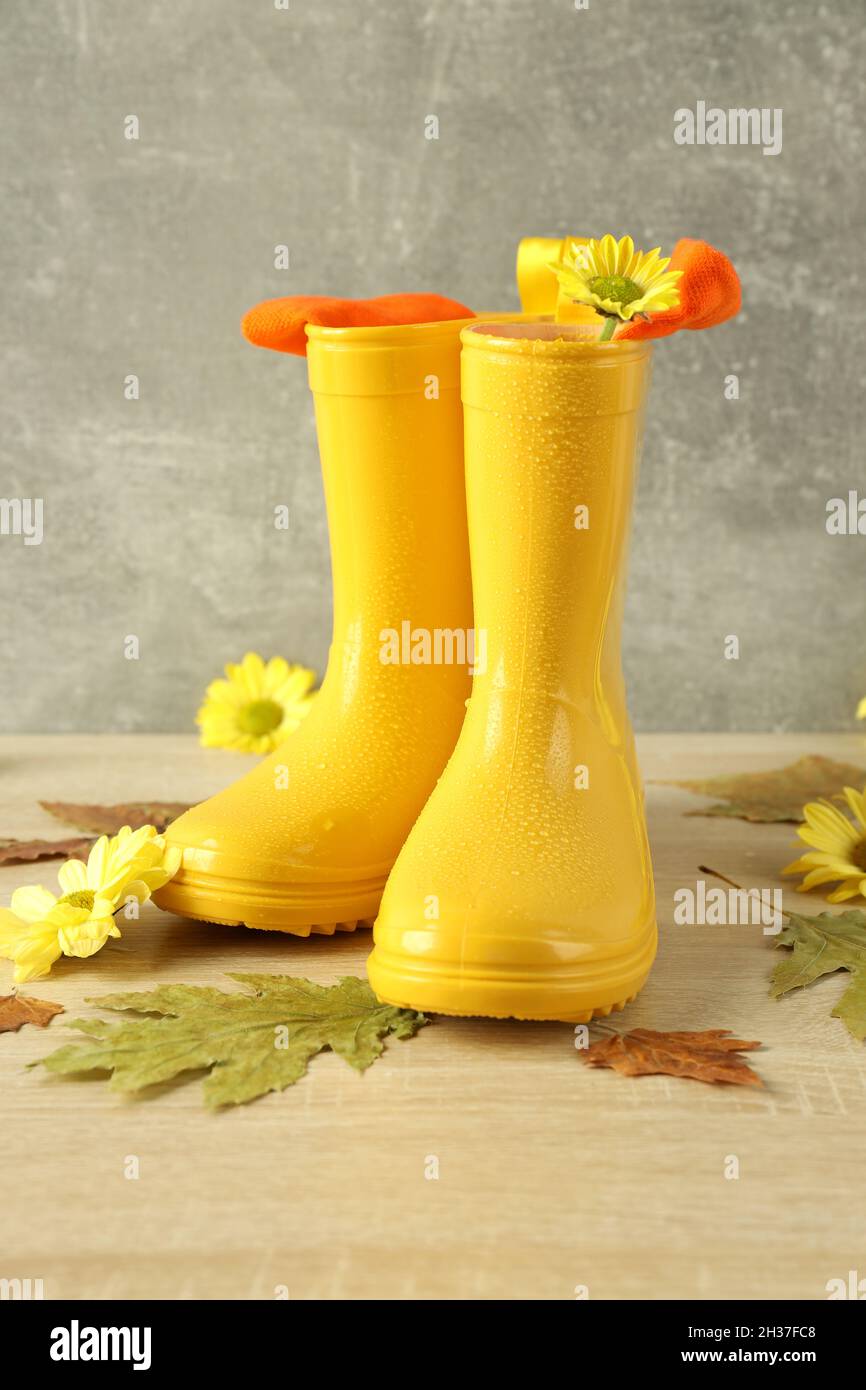 Rubber boots with flowers on wooden table with leaves Stock Photo - Alamy