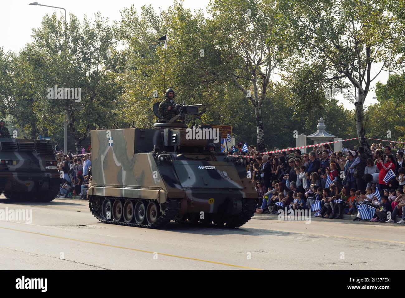 Thessaloniki, Greece - October 28 2019: Oxi Day Greek Army tanks parade. Hellenic military march during national day celebration, with crowd cheering holding flags. Stock Photo