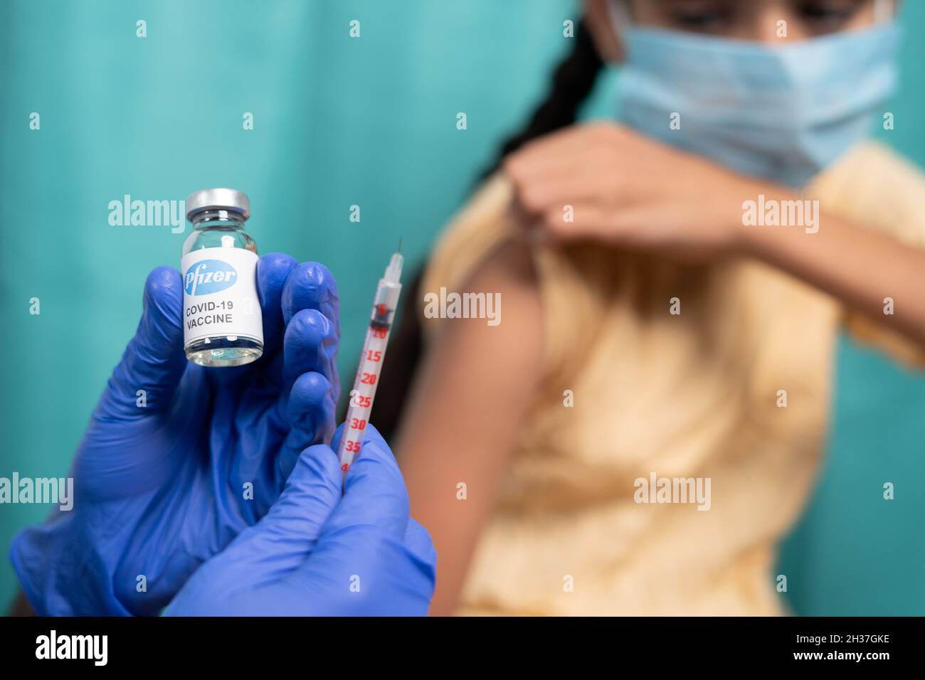 Maski, India - October 26, 2021 : selective focus on vaccine bottle - Kid with medical face mask getting vaccinated Pfizer's Covid-19 or coronavirus Stock Photo