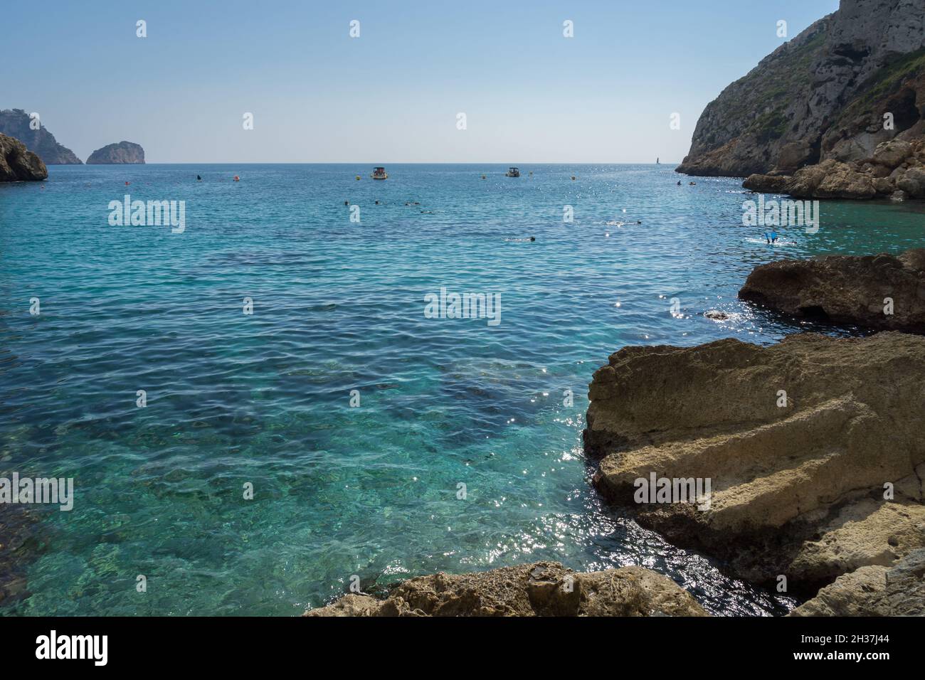 clear turquoise blue water and cliffs in a beautiful bay on the Mediterranean coast in Spain Stock Photo