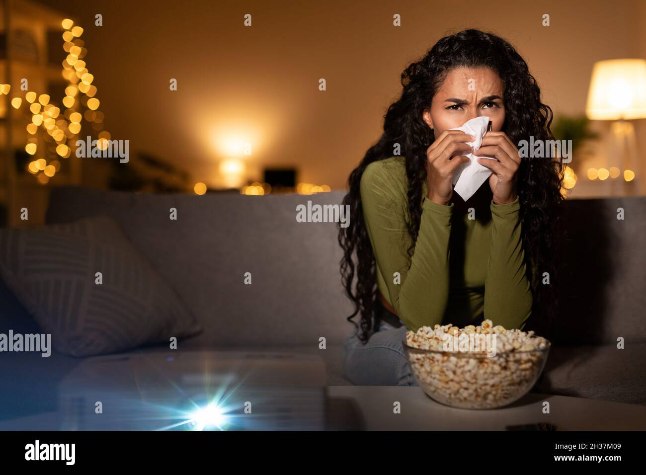 Unhappy Woman Crying Watching Drama Film Using Projector At Home Stock Photo