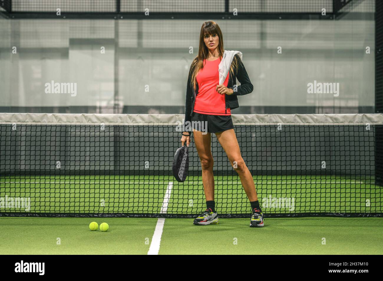 Beautiful girl playing paddle tennis, racket in hand wipes the sweat