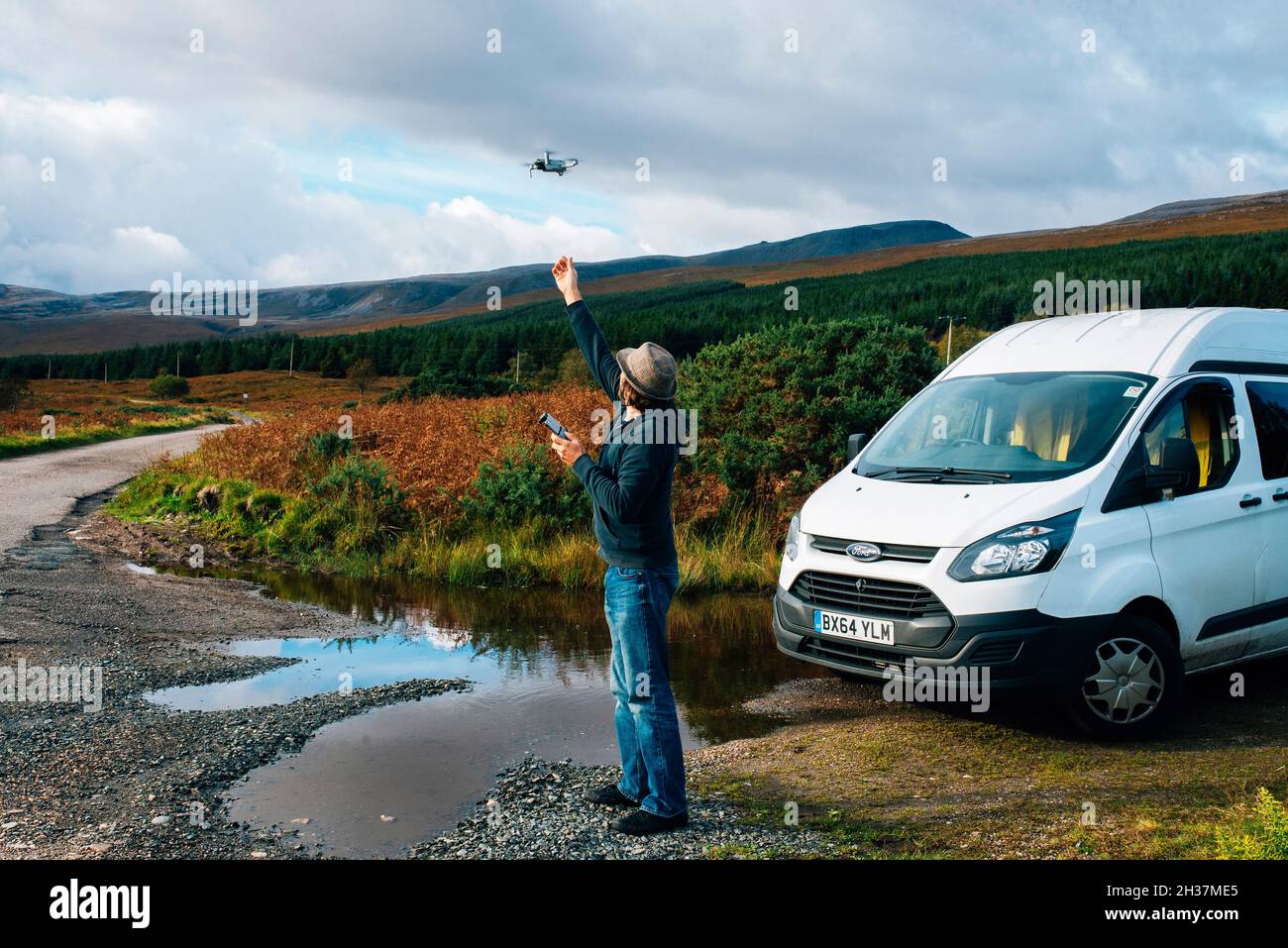 A man flying a drone next to a campervan on the NC 500 route in the scottish highlands Stock Photo