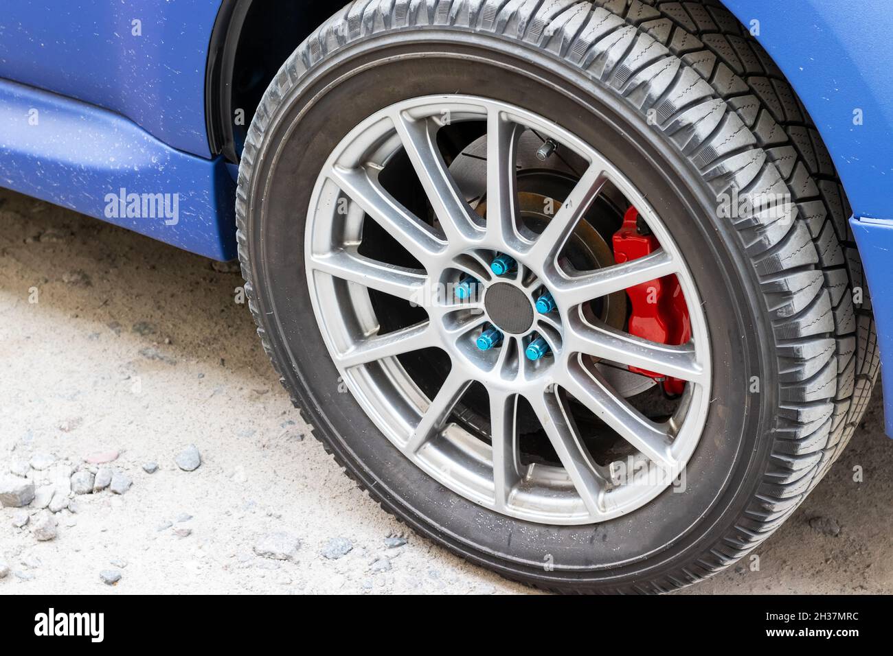 Stylish blue car wheel with red brake caliper and fivenut rim. Brake