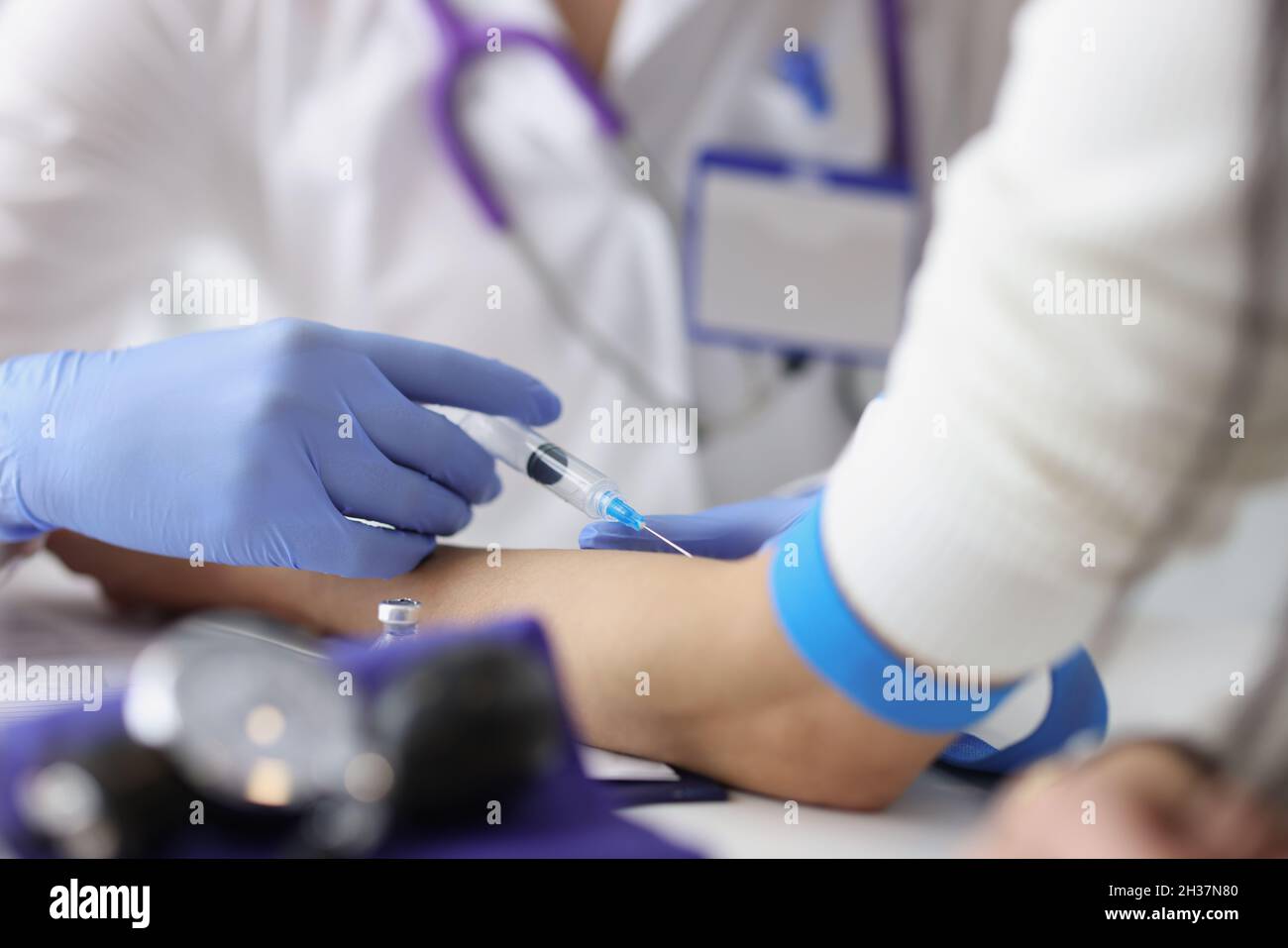 Nurse giving intravenous injection into patient ulnar vein at clinic