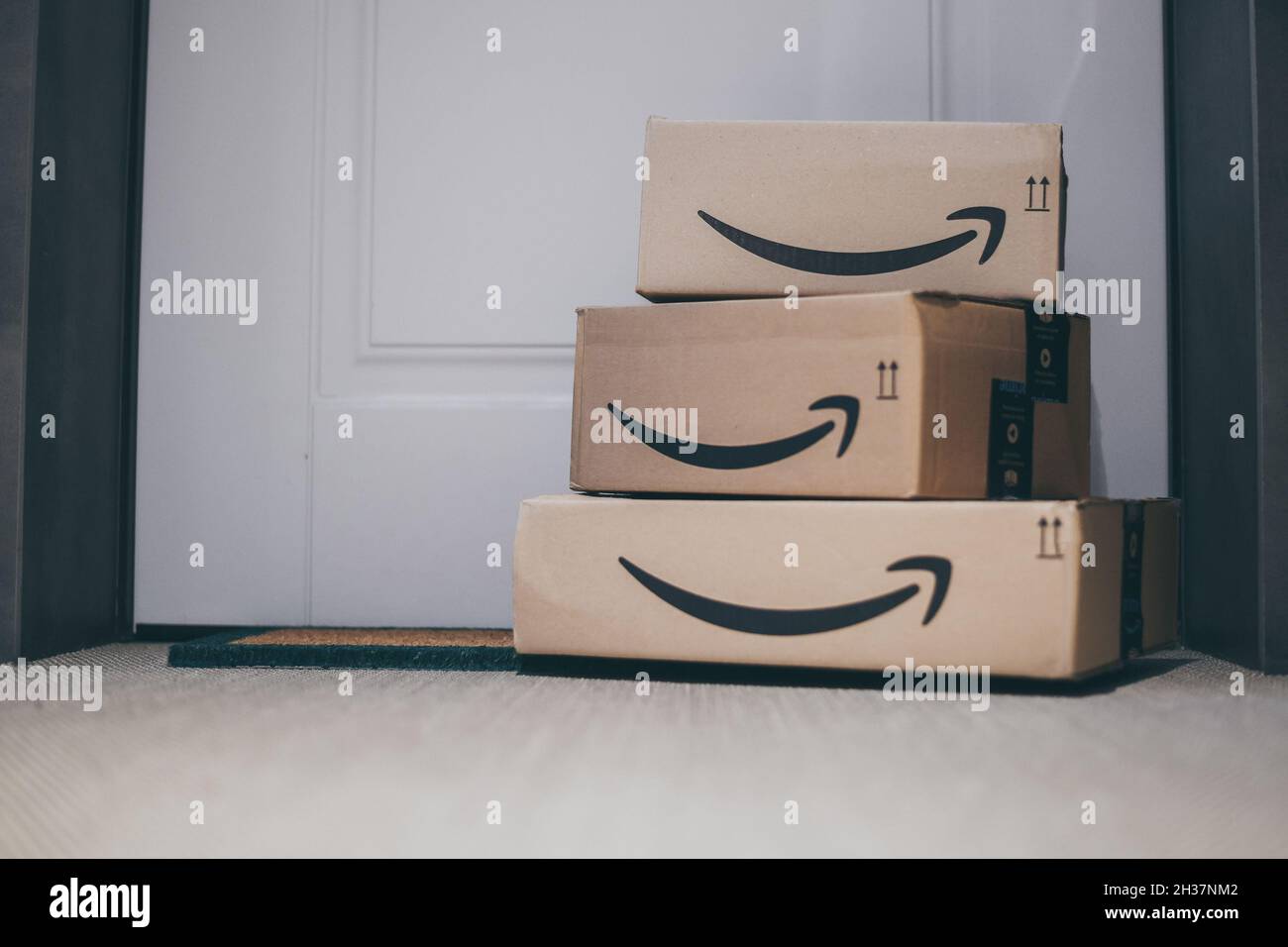 Boxes with Amazon logo in front of the house door. Order on delivery. Christmas gifts in cardboard box on the doormat. Amazon Prime priority delivery. Stock Photo
