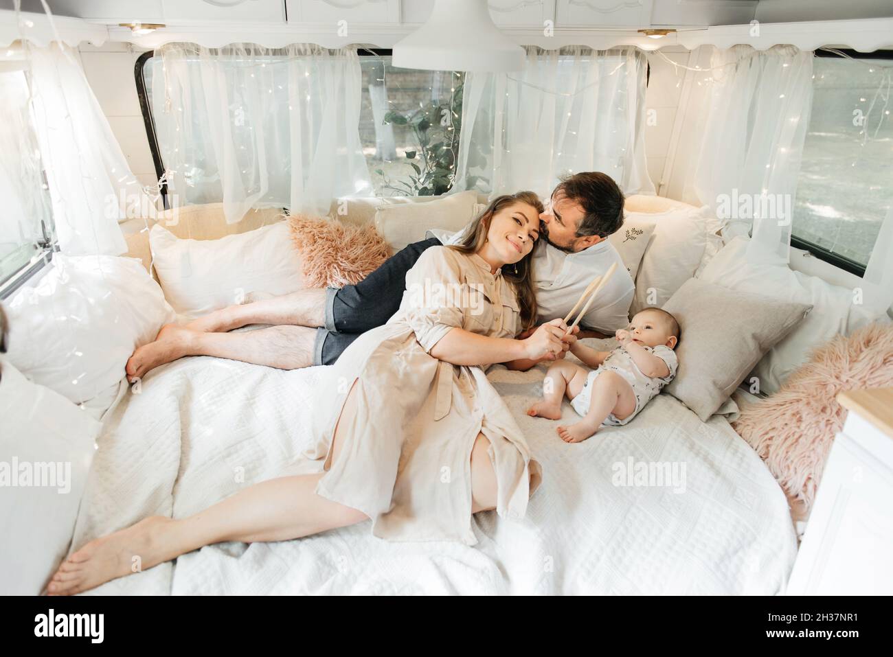 Family with baby on the bed in trailer in the morning. Newborn child