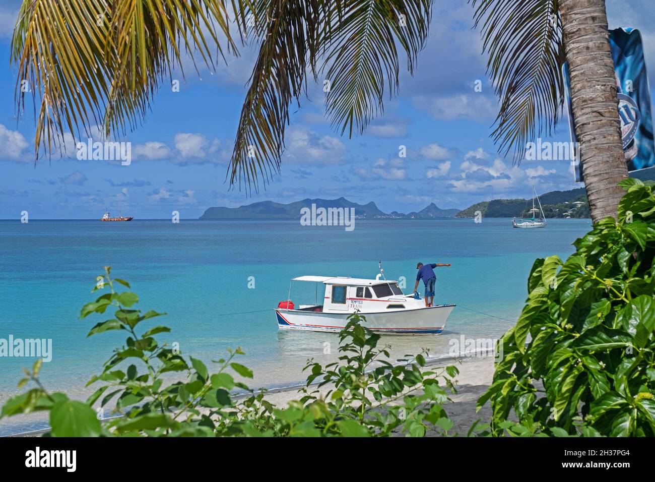 Small fishing boat anchored before Paradise Beach on Carriacou, island of the Grenadine Islands, Grenada in the Caribbean Sea Stock Photo