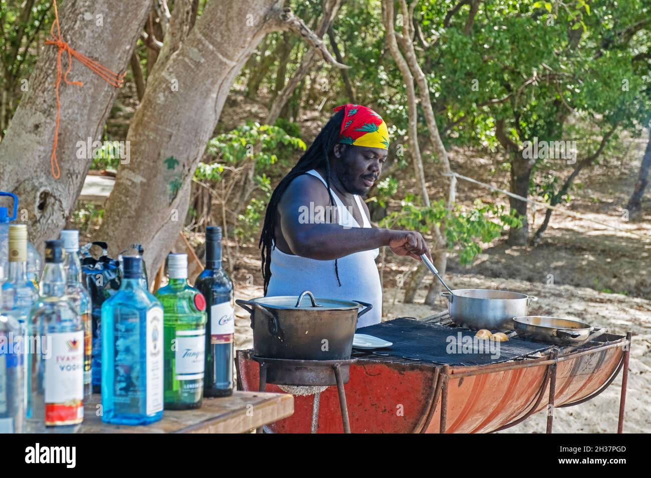 Rastafari cooking meal on barbecue at beach bar at Anse La Roche on Carriacou, island of the Grenadine Islands, Grenada in the Caribbean Sea Stock Photo