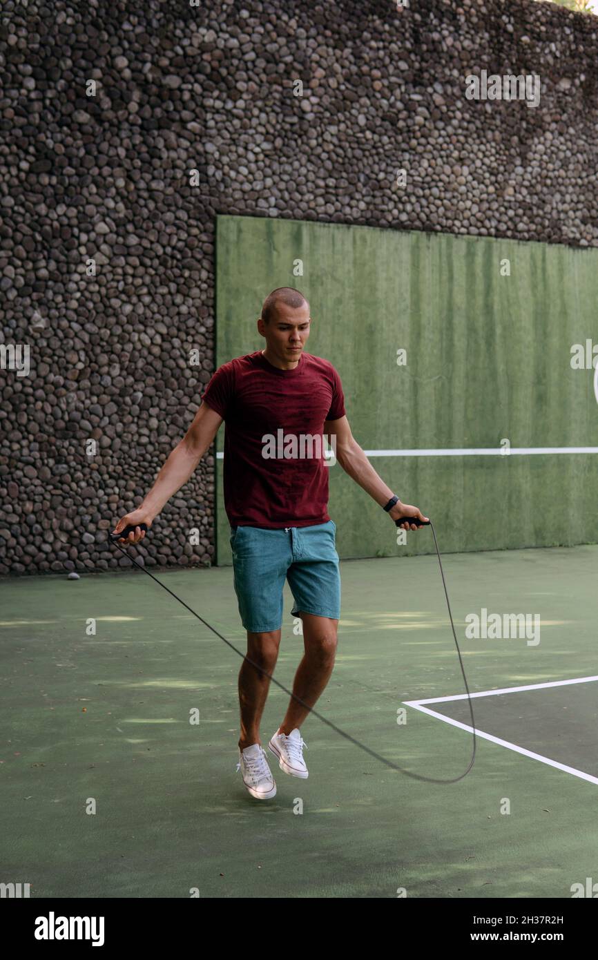 man jumping rope on the tennis court. bali Stock Photo Alamy