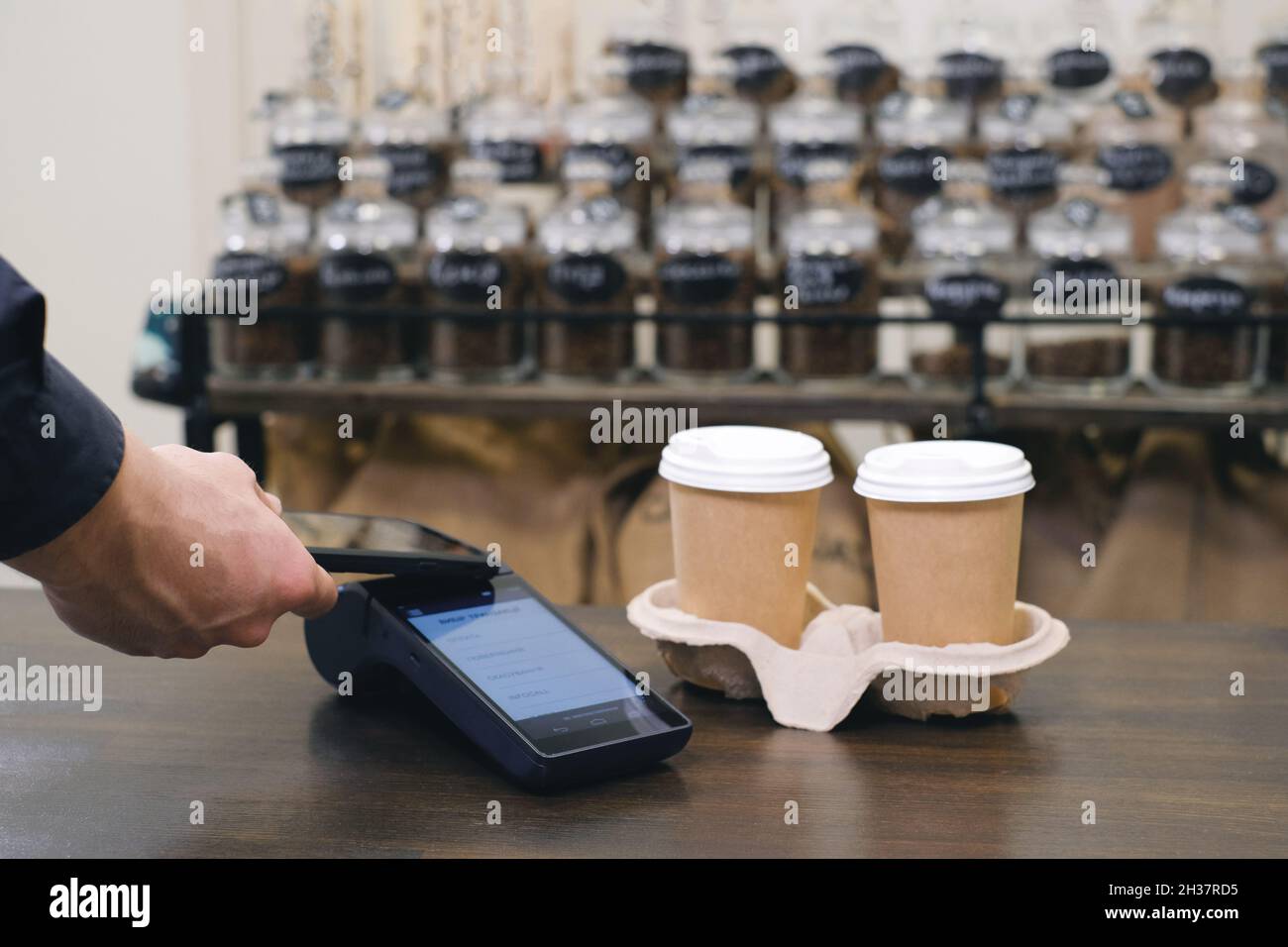 Customer using smartphone and nfs technology to pay barista for purchase with phone at a cafe for coffee. Safe transaction  Stock Photo
