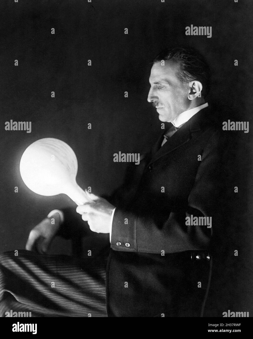 Nikola Tesla (1856-1943), 1919. Tesla in 1919 holding a gas-filled phosphor coated wireless light bulb which he developed in the 1890's to replace incandescent lamp. Stock Photo