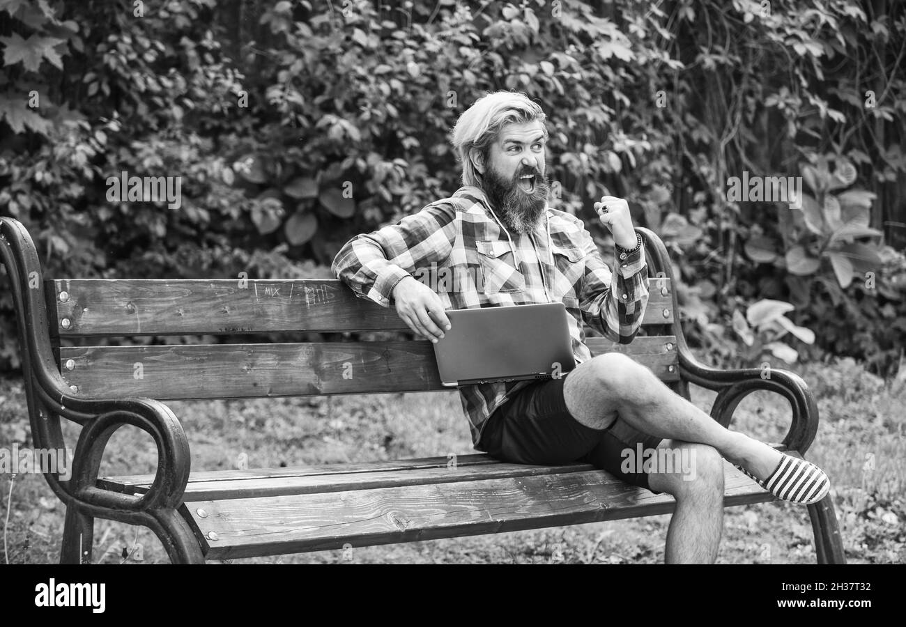 Fresh air. Mobile internet. Modern laptop. Remote job. Online shopping. Agile business. Bearded guy sit bench park nature background. Work and relax Stock Photo