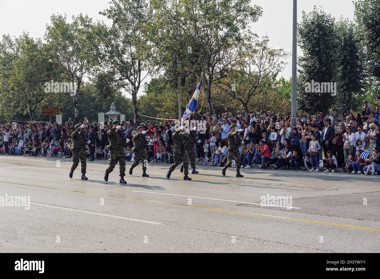 Thessaloniki, Greece - October 28 2019: Oxi Day Greek Army personnel parade holding flag. Hellenic military march during national day celebration, with attending crowd. Stock Photo