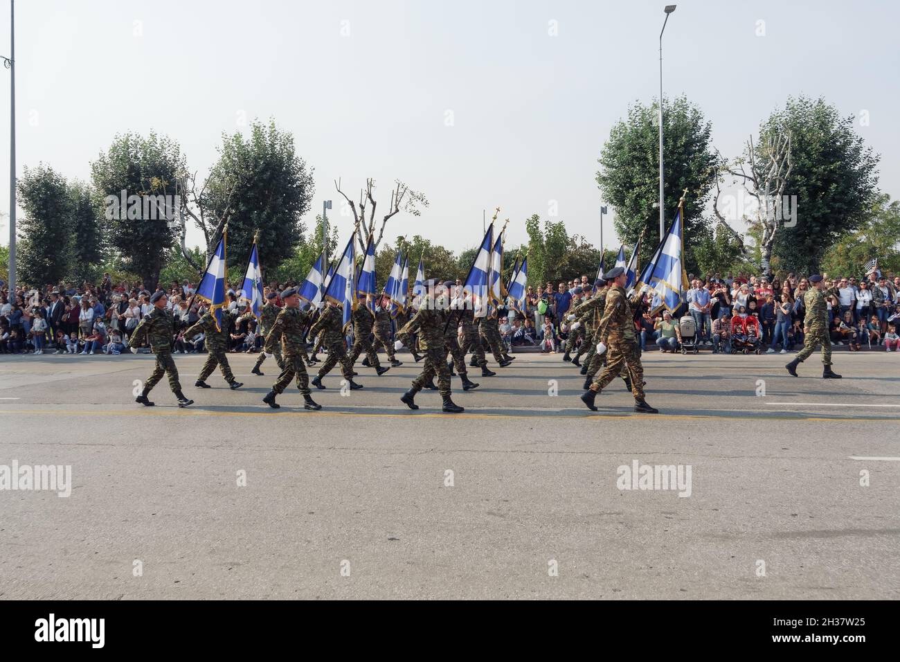 Thessaloniki, Greece - October 28 2019: Oxi Day Greek Army personnel parade holding flag. Hellenic military march during national day celebration, with attending crowd. Stock Photo