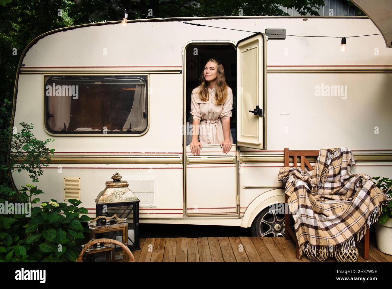 Camping and travelling . Happy person relaxing outdoors near trailer. Woman is ready for road trip Stock Photo