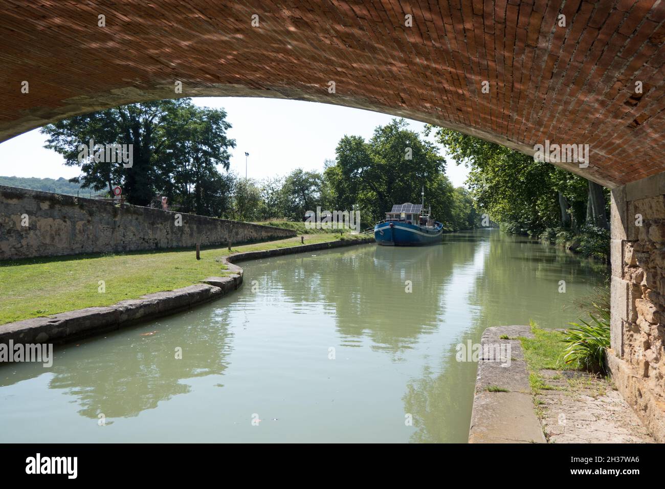 Boat on the Canal du Midi in the department of Aude, region of Occitanie, southern France. View under old bridge Stock Photo