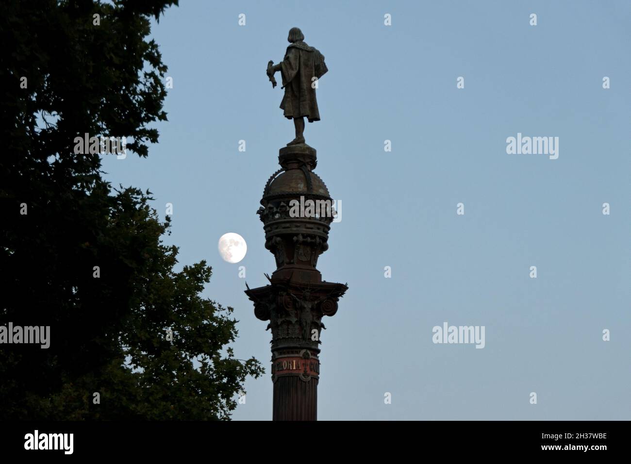 Urban view of Barcelona, Spain with Monument to Columbus and moon shining in sky. Famous Spanish city in Catalonia as travel destination Stock Photo