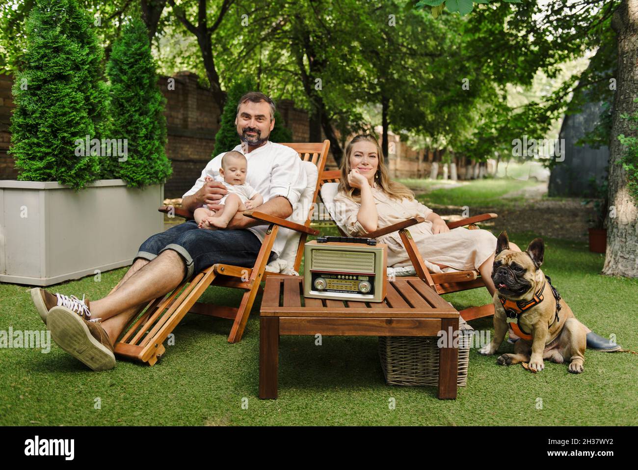 Family with baby boy and dog spending happy time together outside on deck chair, lifestyle  Stock Photo