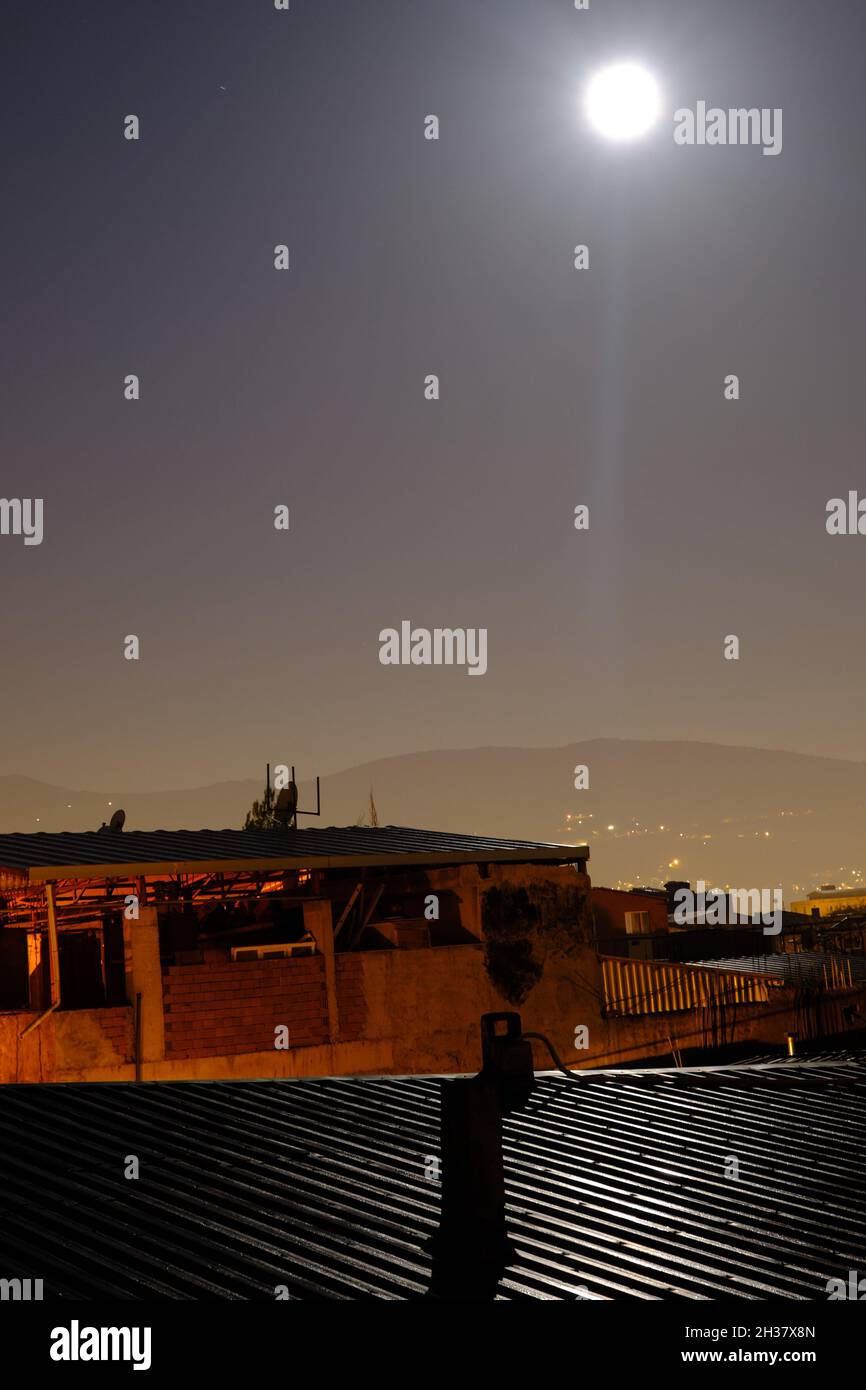Moon and light reflection on the metal roof in ghettos in bursa with ulu mountain (uludag) and city light background. Stock Photo