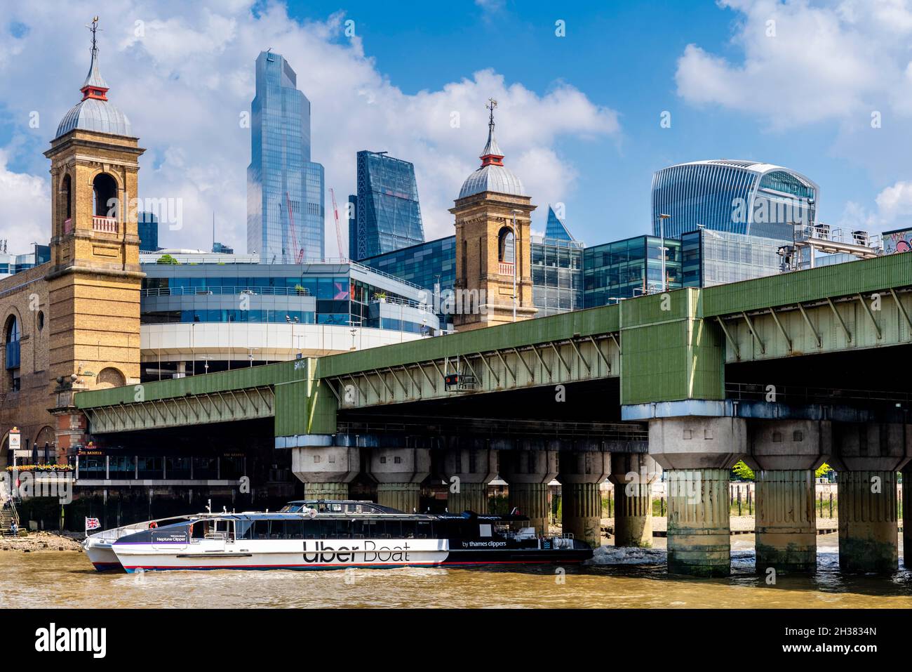 An Uber Boat Sails Under Cannon Street Railway Bridge With Cannon Street Station and The City Of London Skyscrapers In The Backround, London, England. Stock Photo