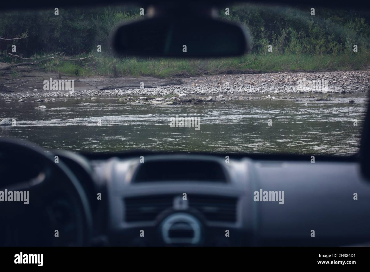 the car is parked on the river bank. the river is visible through the