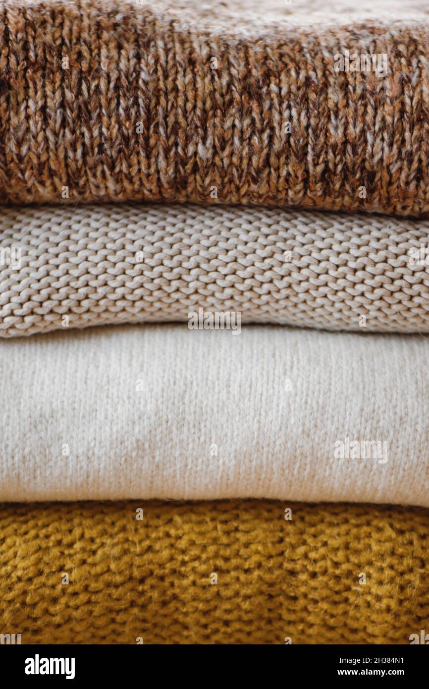 Closeup of knitted warm color sweaters folded in stack. Stock Photo