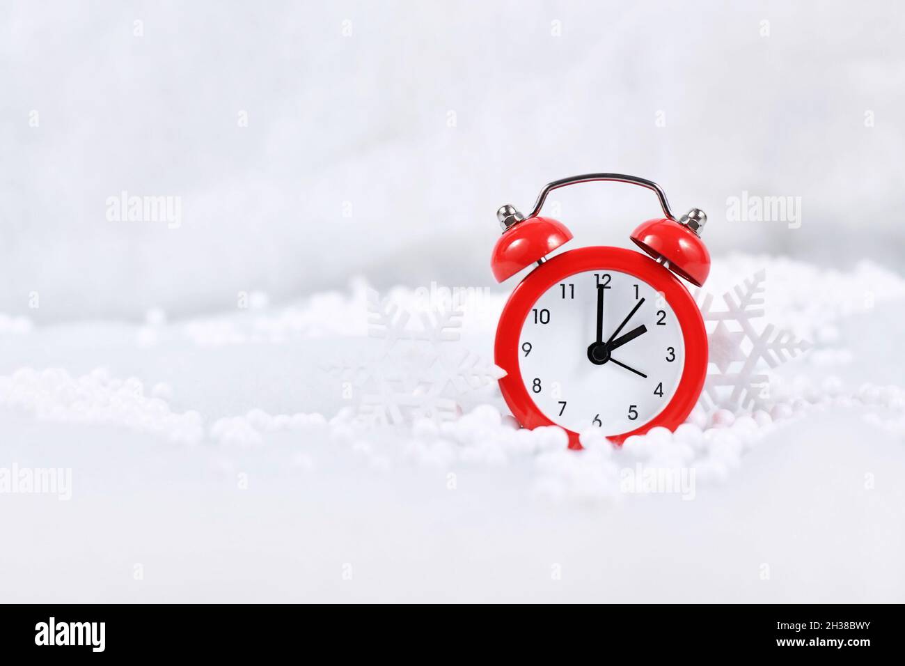 Winter time change for daylight saving in Europe on October 31st concept with red alarm clock between snow with copy space Stock Photo