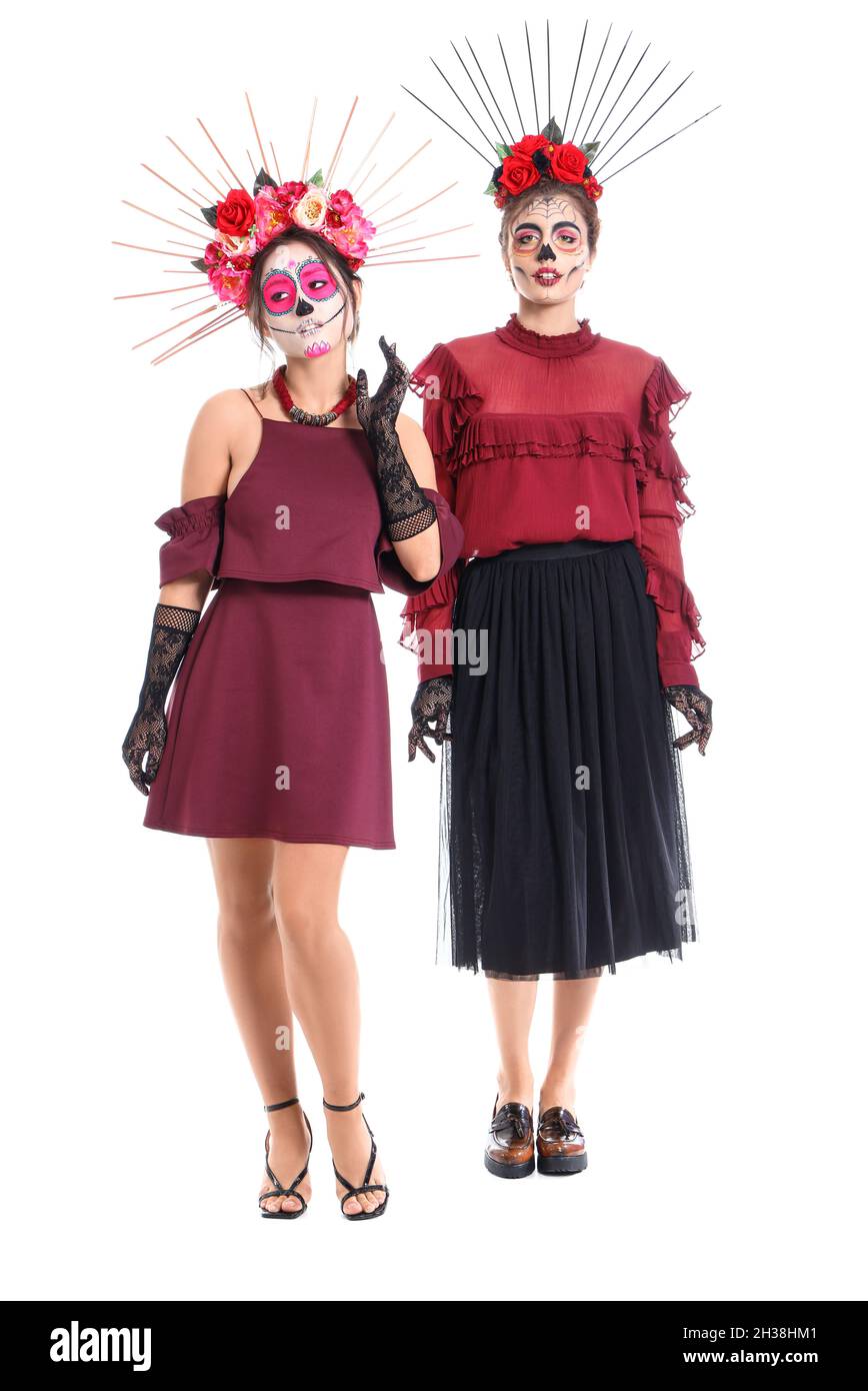 Stylish women with painted skull on faces against white background. Celebration of Mexico's Day of the Dead (El Dia de Muertos) Stock Photo