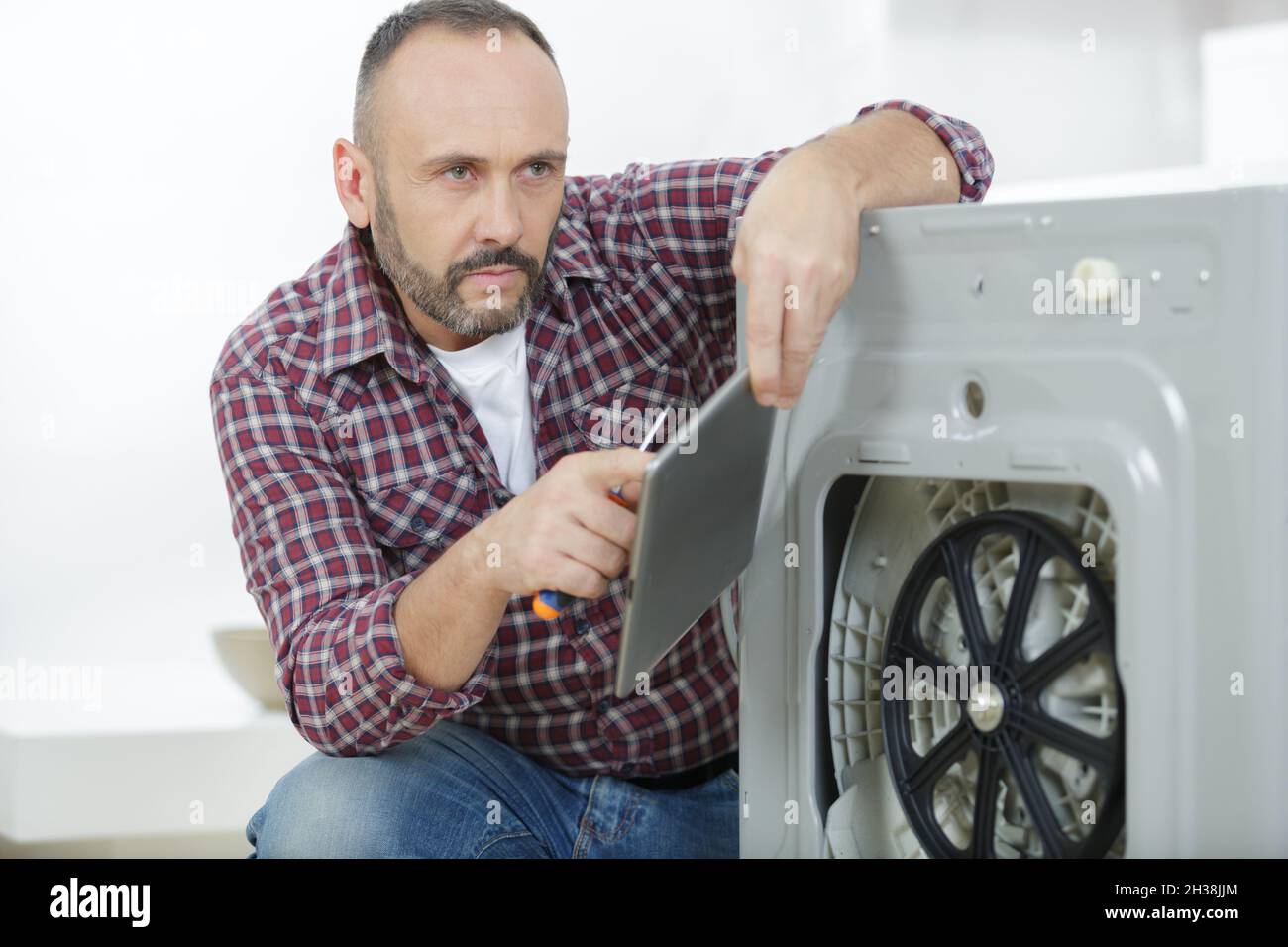 man using tablet to fix the washing machine Stock Photo