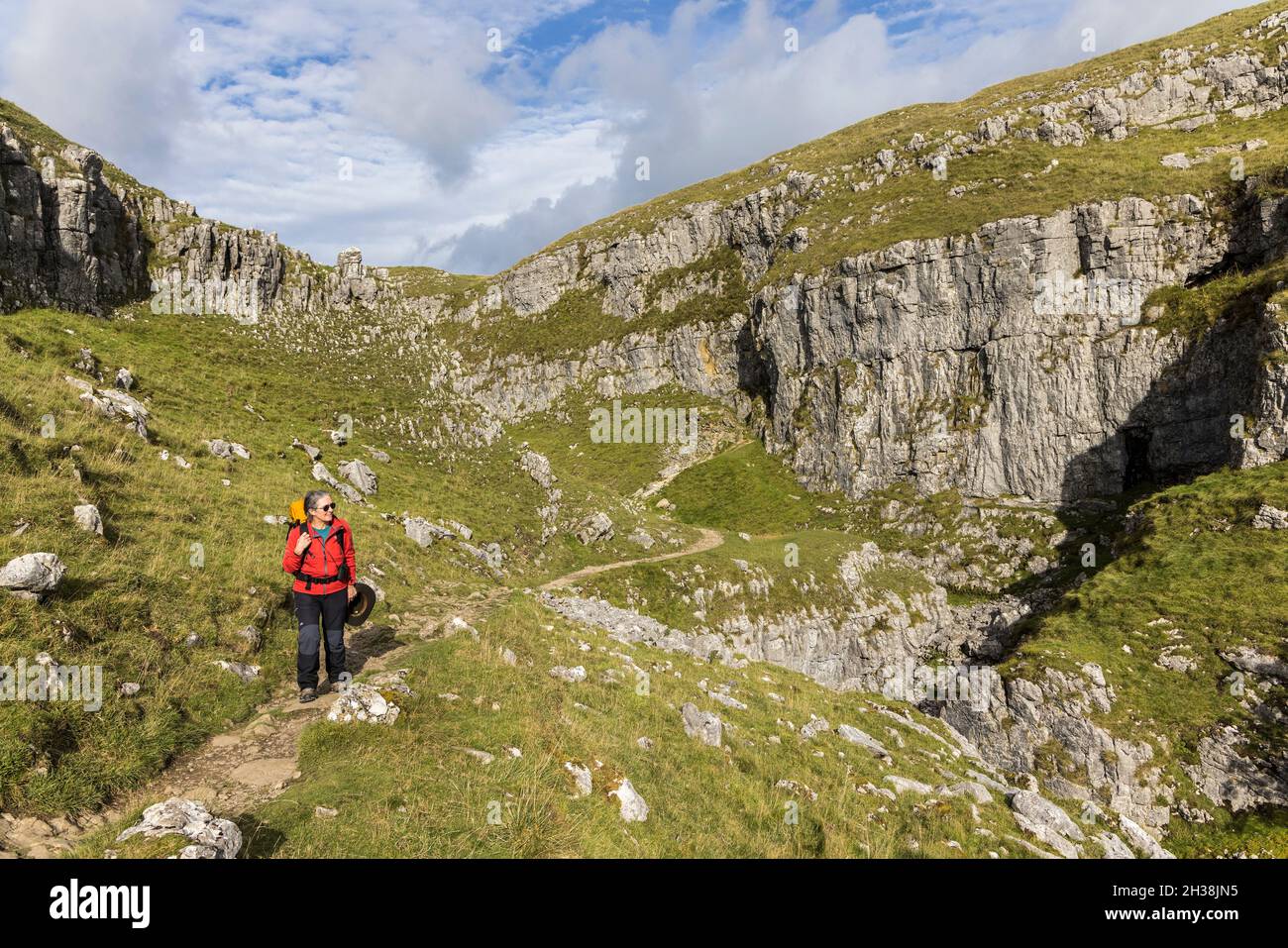 Walker on track through the Watlowes approaching Malham Cove on the Pennine Way, Yorkshire Dales, UK Stock Photo