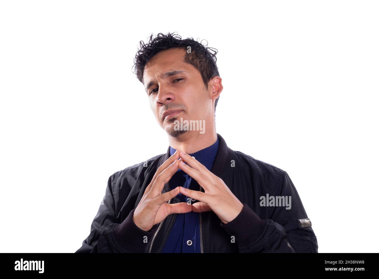 Cunning man plotting something isolated on white background. Young adult Latino man expressing evil or desire for revenge while clasping his fingers Stock Photo