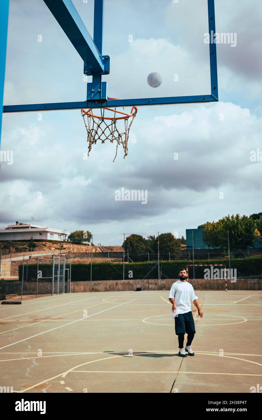 Young boy throwing a basketball to basket on a court Stock Photo Alamy