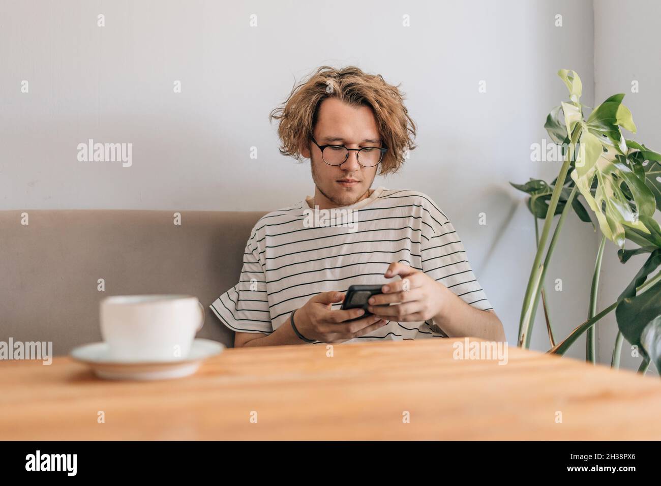 Teenager young man writes sms in cafe. Stock Photo