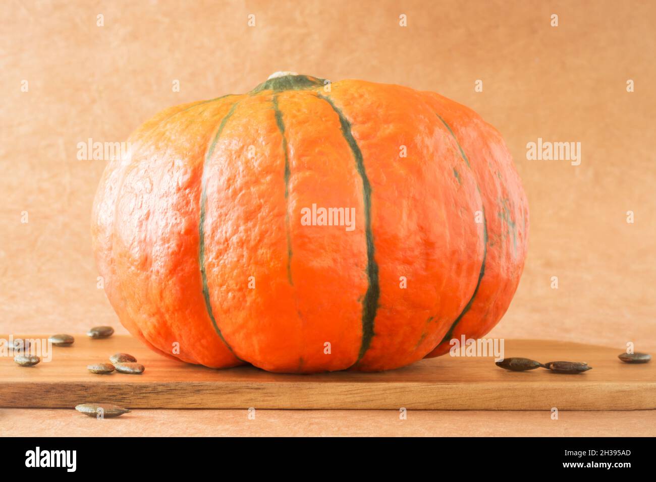 Orange pumpkin and seeds on kitchen board on beige background in horizontal format Stock Photo